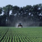 A tractor spraying herbicide onto a soybean field.