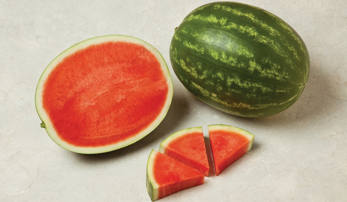 a watermelon cut in half showing the inside with a few cut triangular pieces next to it